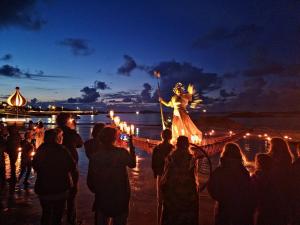 a crowd of people watching a woman on a bridge with lights at Arranmore Glamping in Aphort