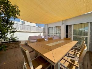 Une grande table et des chaises en bois sont disponibles sur la terrasse. dans l'établissement Luxury Duplex 200 M2 Terrace Parking StayInSeville, à Séville
