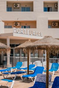 a group of lounge chairs and umbrellas in front of a hotel at Port Europa in Calpe