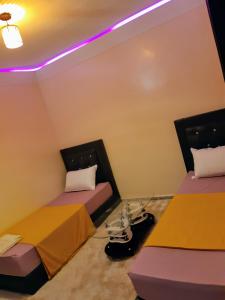 2 bedden in een kamer met paarse verlichting bij Résidence London in Laayoune