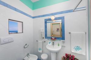 a bathroom with a sink and a toilet and a mirror at Hotel Ossidiana Stromboli Center in Stromboli