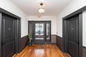 an empty hallway with black doors and wooden floors at Steps to Bathhouses, Historic Downtown Apartment Room # 201 in Hot Springs