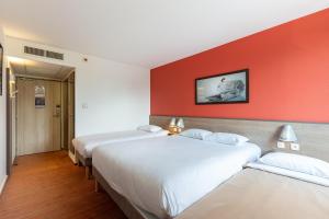 three beds in a room with a red wall at Ace Hotel Chateauroux Déols in Déols