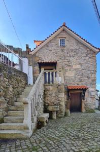 een oud stenen gebouw met een trap en een deur bij Stone House in Salzedas