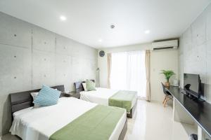 Hotel Paradiso Miyakojima في جزيرة مياكو: غرفة فندقية بسريرين وتلفزيون بشاشة مسطحة