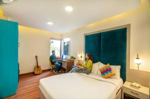 una mujer sentada en una cama en una habitación de hotel en goSTOPS Delhi, en Nueva Delhi