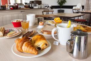 a table with plates of breakfast foods and coffee at Ace Hotel Chateauroux Déols in Déols