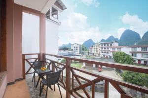 a balcony with chairs and a view of mountains at Yangshuo Xiao Long River Hotel in Yangshuo