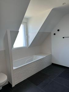 baño blanco con bañera y aseo en Maison Ker Ria, en Locoal-Mendon