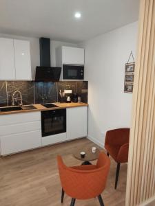 a kitchen with white cabinets and a table and a chair at Appartement, centre Langres 2 in Langres
