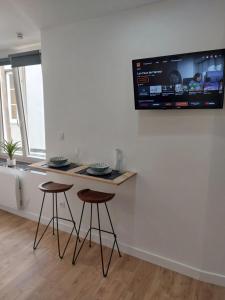 a kitchen with two bar stools and a tv on the wall at Appartement, centre Langres 2 in Langres