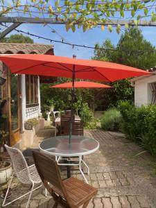 una mesa con una sombrilla roja en el patio en Maison d'hôtes Le Beauséjour, en Carcassonne