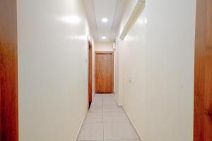 a hallway with white walls and a wooden door at FabExpress SK Prime in Ujjain