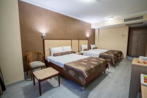una habitación de hotel con 2 camas y una silla en HALLEY OTEL en Denizli