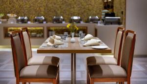 Una mesa de madera con dos sillas y una mesa con servilletas. en Click Hotel Bhuj, en Bhuj