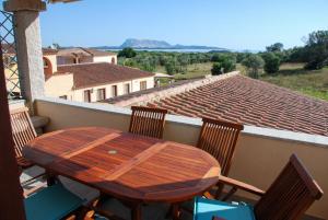 ein Holztisch und Stühle auf einem Balkon in der Unterkunft La Terrazza sul Mare in San Teodoro