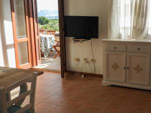 ein Wohnzimmer mit Fernseher und einer Tür zu einer Terrasse in der Unterkunft La Terrazza sul Mare in San Teodoro