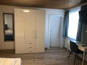 1 dormitorio con armario blanco y escritorio en Hotel Weismann, en Sankt Georgen im Attergau