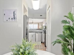 uma cozinha com paredes brancas e uma mesa com uma planta em Sea Winds 501 - Corner Breeze em Ormond Beach