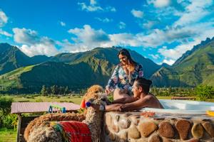 a man and woman sitting next to a hot tub with mountains at Inkasaire Boutique Lodge in Urubamba