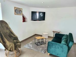a living room with a green couch and a tv at Petit loft, maison bord de mer in Pirou
