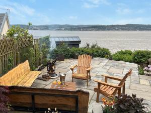 a patio with two chairs and a table with a view of the water at Shore House in Kilcreggan