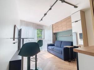 Una sala de estar con un sofá azul y una cocina. en SMART Studio ultra connecté - Escale parfaite entre Disneyland et Paris, en Noisy-le-Grand