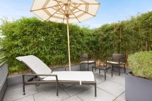 a patio with three chairs and an umbrella at Rocco Forte Hotel De Rome in Berlin