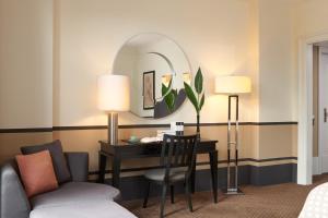 Cette chambre comprend un bureau et un miroir. dans l'établissement Rocco Forte Hotel De Rome, à Berlin