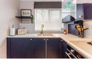 een keuken met blauwe kasten, een wastafel en een raam bij Hardwick House 3 bed with parking for Contractors & Tourists in Gateshead