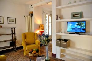 a living room with a yellow chair and a television at Il giardino dei limoni casa nel Borgo in Maranola