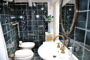 a black tiled bathroom with a toilet and a sink at Il giardino dei limoni casa nel Borgo in Maranola +20 photos