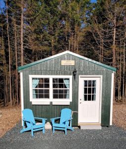 a green shed with two blue chairs in front of it at Lighthouse Cabins Maine in Bass Harbor