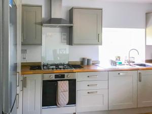 a kitchen with white cabinets and a stove top oven at Hempstead End in Lessingham