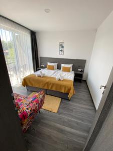 Habitación de hotel con cama y silla en HOTEL CSOPAK Resort & Lake, en Csopak