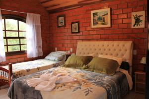 a bedroom with a bed and a brick wall at Emy Pousada in Monte Verde