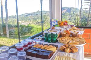 a buffet of food on a table in front of a window at Emy Pousada in Monte Verde