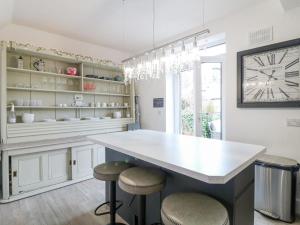 cocina con encimera grande con taburetes y reloj en Matlock Maisonette, en Matlock