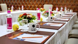 una mesa larga con mesas marrones y blancas con flores y botellas en Click Hotel Bhuj, en Bhuj