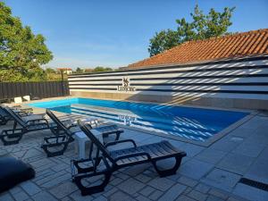 Una piscina con tumbonas al lado de una casa. en Leonchic - Guest House com Piscina de Água Salgada, en Barcelos