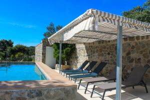 a group of chairs under an umbrella next to a swimming pool at Quinta do Miradouro in Portalegre