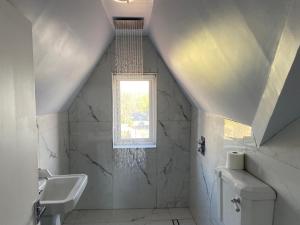 a white bathroom with a sink and a window at Croydon Victorian 1-Bed Penthouse Sleeps 2 in London