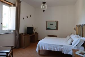 a bedroom with a white bed and a television at Villa Puolo - With Private Sea Access in Sorrento