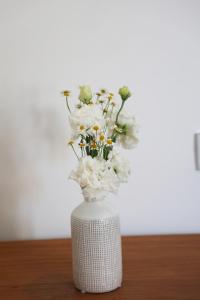 Villa Puolo - With Private Sea Access في سورينتو: مزهرية بيضاء مليئة بالورود البيضاء على الطاولة
