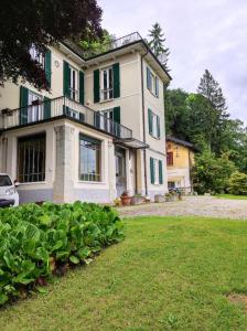 ein großes weißes Haus mit grünen Rollläden in der Unterkunft Villa Virginia in Varese