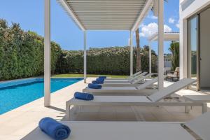 a row of lounge chairs next to a swimming pool at Villa Marc II in Sant Jordi
