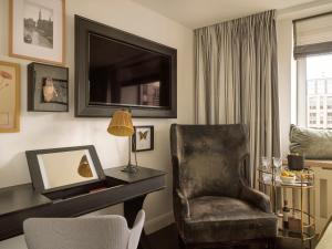 a living room with a chair and a television at The Nikolai Hamburg - Leonardo Limited Edition in Hamburg