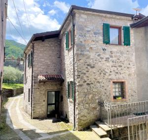 a stone house with green shutters and a door at Tre Terre in Mulazzo