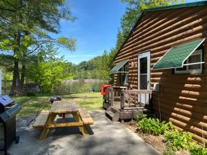 a picnic table in front of a log cabin at Adirondack Waterfront Cabin Upper Hudson Tributary in Lake Luzerne
