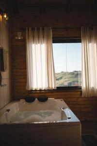 a bath tub in a room with a window at Chico Cabanas in Lajeado Grande